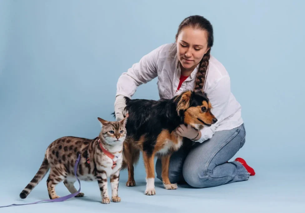 Woman petting a dog and a cat sitting nearby.